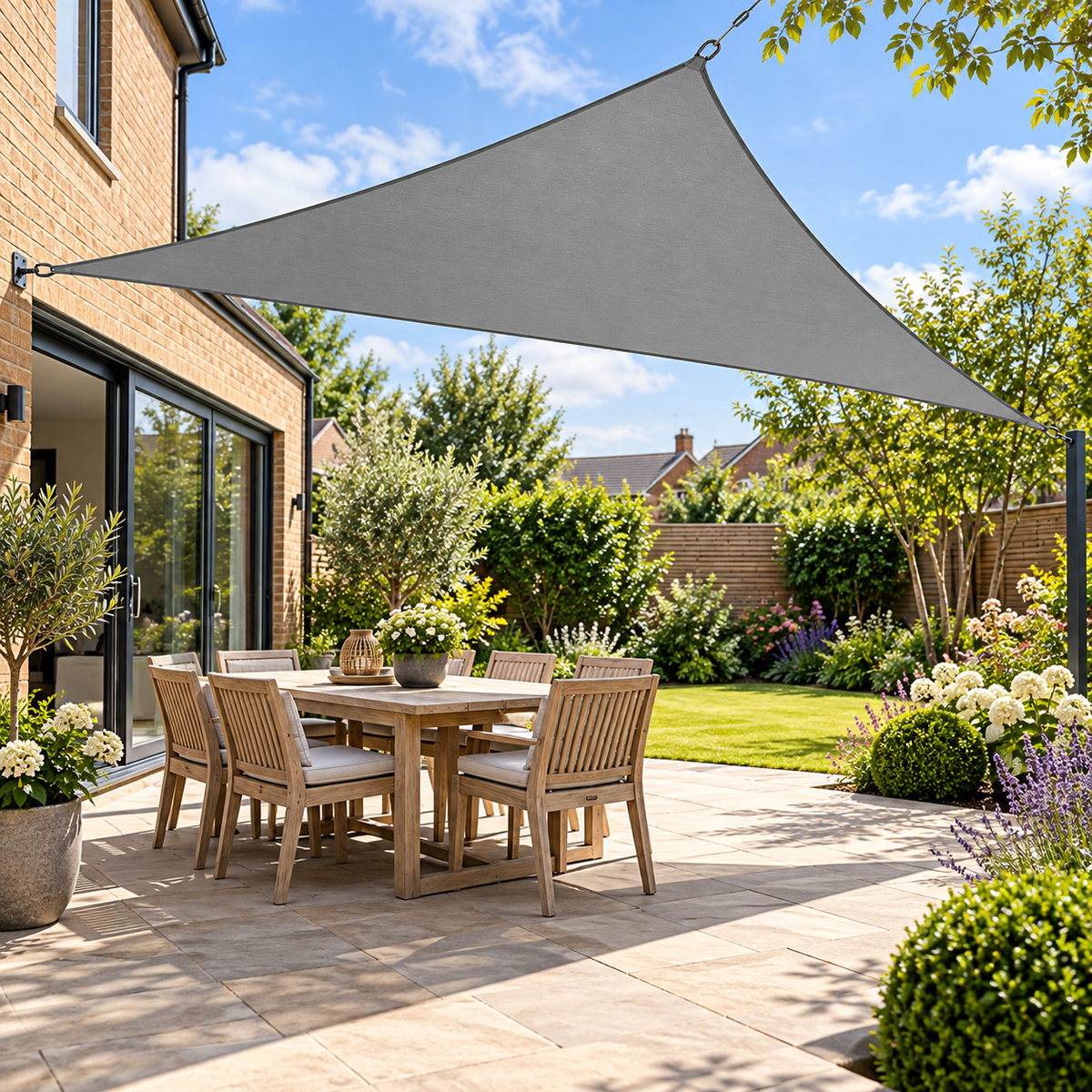 Grey triangle outdoor shade sail canopy over a garden patio dining set